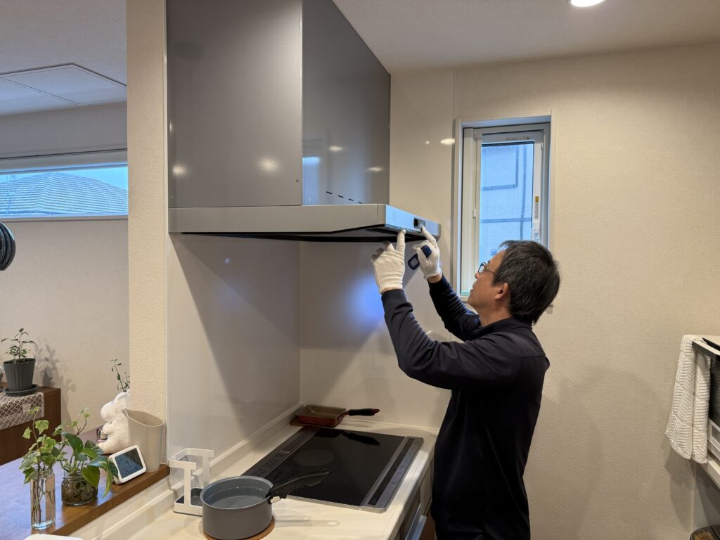姫路の工務店YSHOMEによる新築住宅の6ヶ月点検の様子。スタッフがキッチンのレンジフード（換気扇）を丁寧に確認している写真。